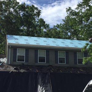 A two-story home in the process of having shingles installed.