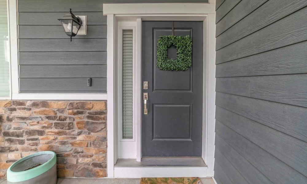 Entrance to a house with side light and gray front door decorated with wreath